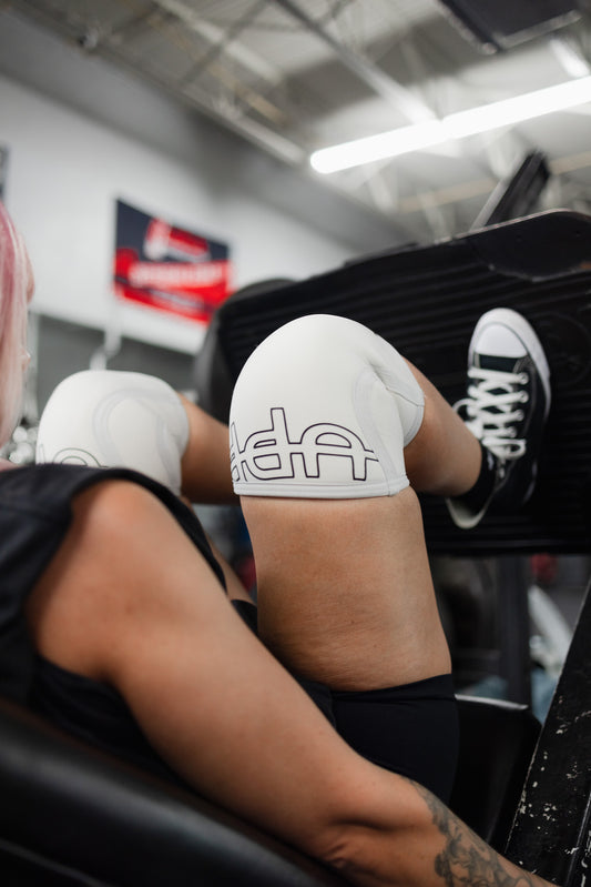 woman doing leg press with uppper knee sleeves white